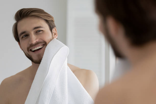 istock Mirror reflection smiling young man wiping face with white towel 1265210570