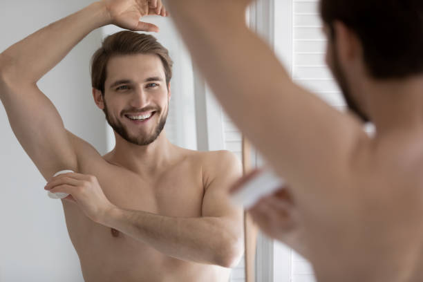 istock Mirror reflection smiling young man applying antiperspirant on armpit 1265210579