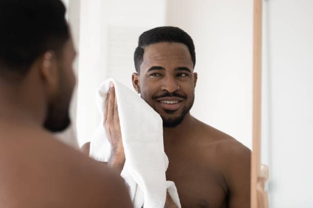 istock Mirror reflection smiling African American man wiping face with towel 1265210650