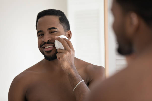 istock Head shot mirror reflection African American man using cleansing sponge 1265210652