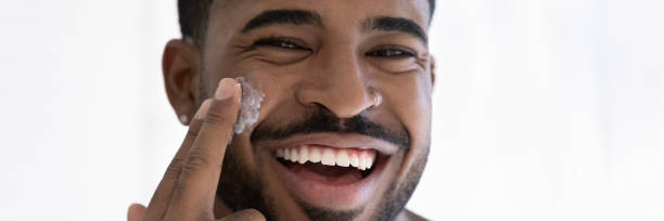 istock Close up overjoyed African American man applying moisturizing face cream 1265210661