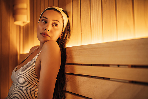 Attractive young woman relaxing in sauna at a spa center.