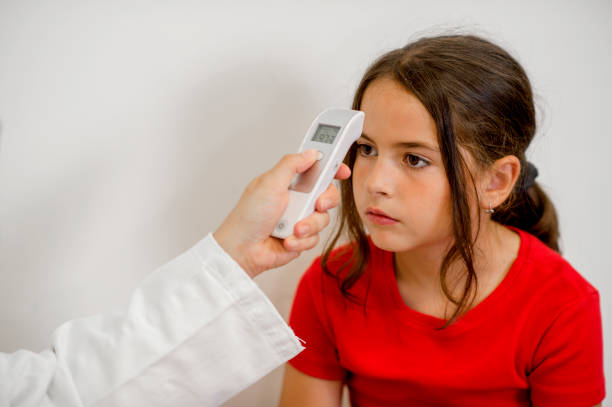 Healthcare worker measuring girl's temperature on thermometer at doctors office