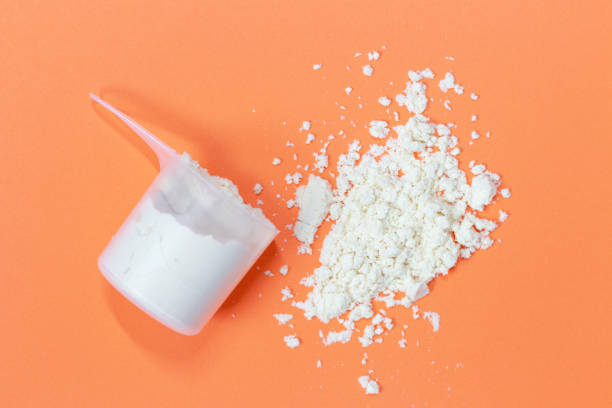 istock Scoop with scattered protein powder, side view on orange background 1265217268