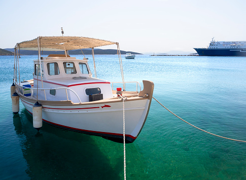 White fishing boat with an awning in the port of the Greek resort town of Marmari on the island of Evia in Greece