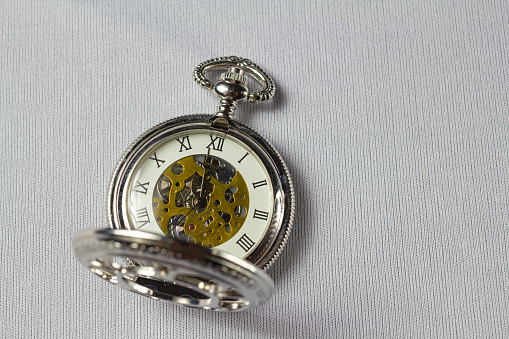 Old classical Pocket watch on white fabric background.