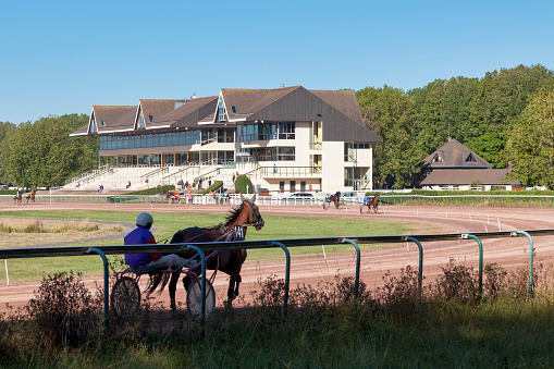 Skilled Racehorse Trainer Breezing a Thoroughbred at a High Rate of Speed on a Dirt Track on a Sunny Day in the Spring