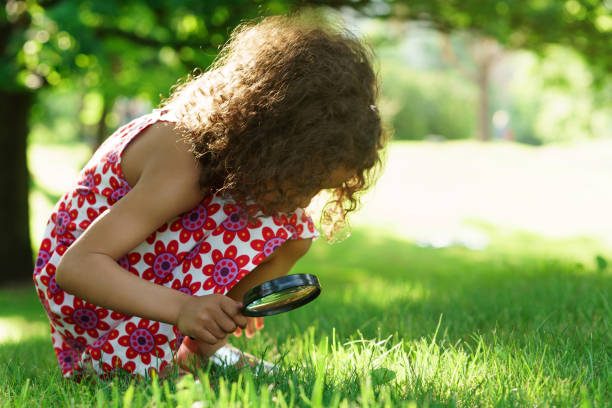 istock Little black girl with looking through magnifying glass 1265225109