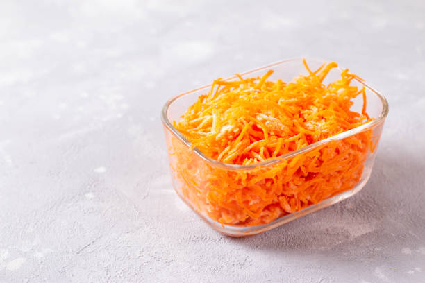 istock Frozen grated carrots in a glass container on a light background 1265226136