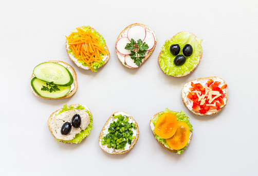 Sandwiches or tapas of their white bread with delicious healthy ingredients on white background. Healthy breakfast