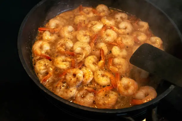 May 9, 2020 - Warsaw, Poland:  Shrimps, scampi frying in a skillet, pan - hot appetiser with butter, garlic, seasoning, close up, top view.