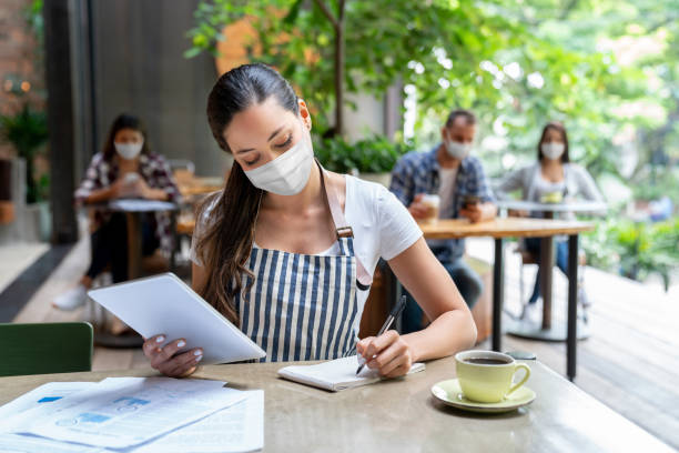 istock Business manager doing the books at a restaurant wearing a facemask 1265230990