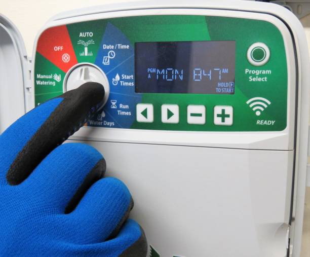 Water Sprinkler System Timer, Senior Man's Hand Senior man's hand, in a glove, setting timer on water sprinkler system. Gardener. Horticulturist. christine kohler stock pictures, royalty-free photos & images