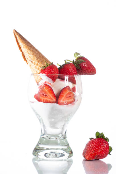 istock Glass with white ice cream strawberries and waffle cone on a glass table on a white background 1265231356