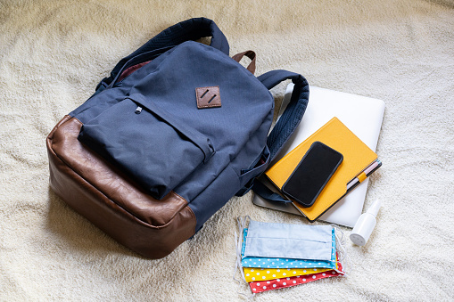 Backpack with school supplies: sanitiser, protective face masks, pens, mobile phone