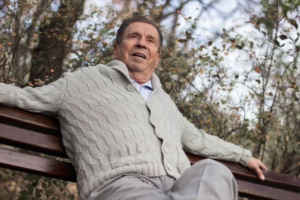 istock Senior man sitting on bench in the park 1265239373