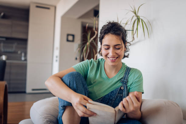 istock Happy young woman enjoying while reading a book at home 1265249137