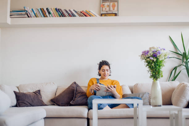 istock Girl sitting on the sofa, reading and enjoying 1265249143