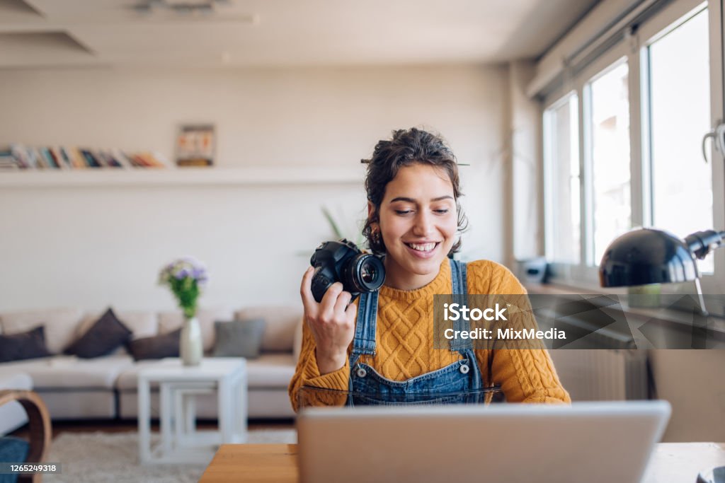 Young photographer working on her photos at her home office Young photographer working at her home office. Photographer Stock Photo