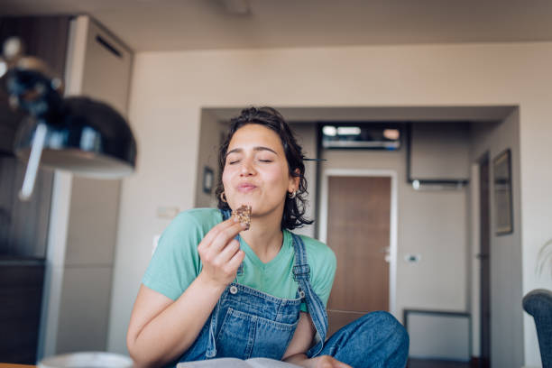 Girl enjoying her favorite cookie at home Happy girl reading, eating a cookie and enjoying at home. enjoyment stock pictures, royalty-free photos & images