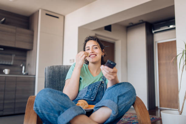 happy girl watching tv in the morning and having breakfast - breakfast eating people teens imagens e fotografias de stock