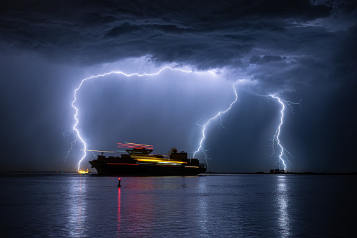 Container ship is leaving the port of Antwerp during a severe thunderstorm. Light trails due to movement of the ship.