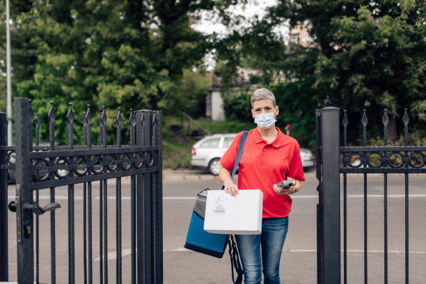 istock Delivery woman with a protective mask arriving to deliver ordered package 1265251201