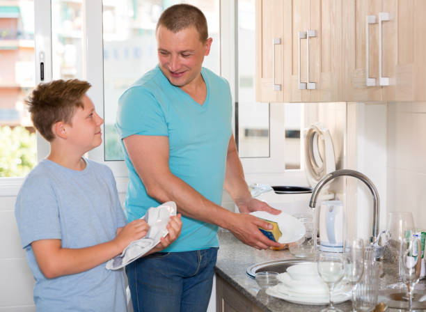 istock Man with his son are washing dishes on the kitchen 1265255605