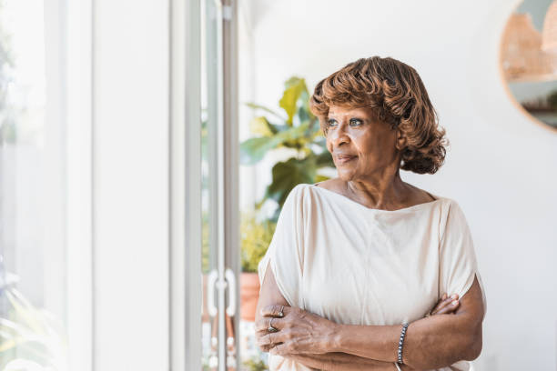Reflective senior woman looking through window