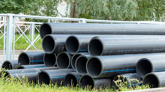 black sewer pipes on the construction site are stacked on top of each other