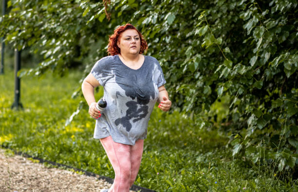 spocona otyła kobieta biegająca na łychady na bieżni, wykonująca trening odchudzania - running jogging treadmill weight training zdjęcia i obrazy z banku zdjęć
