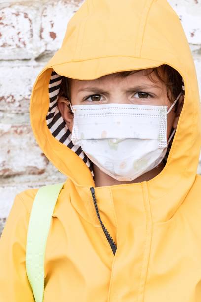 istock Serious annoyed schoolboy looking at the camera using a protective face mask 1265265044