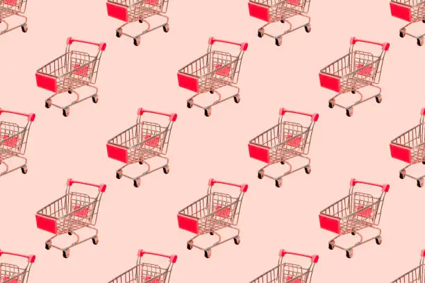 Photo of Shopping cart seamless pattern on pastel pink background.