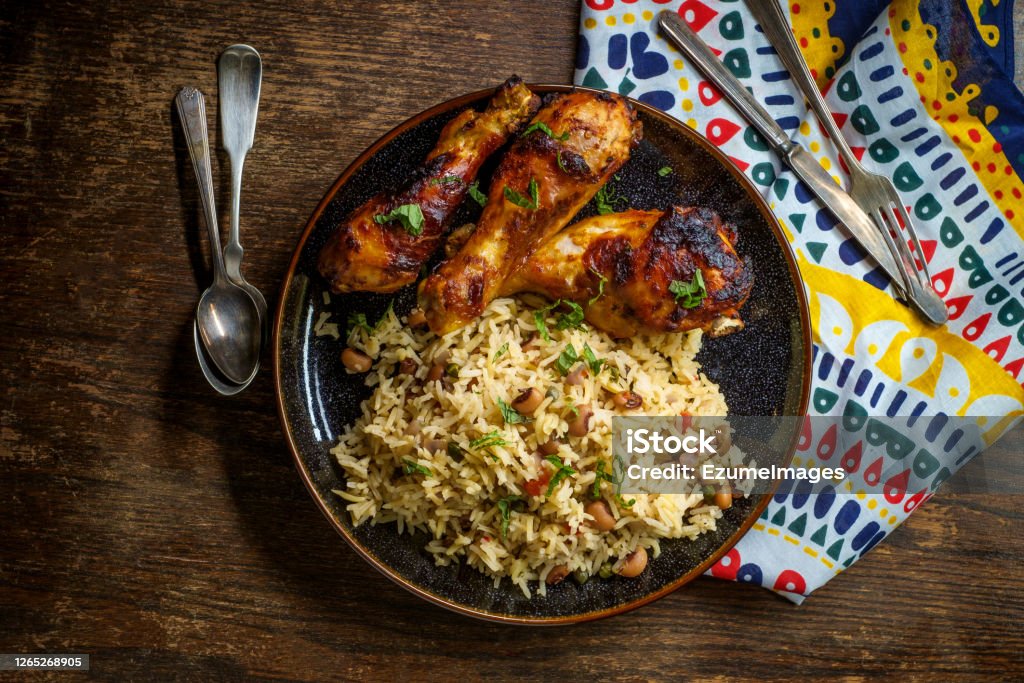 Barbecue Chicken Jollof Rice African cuisine grilled chicken legs with jollof rice with orzo and black eyed peas Rice - Food Staple Stock Photo