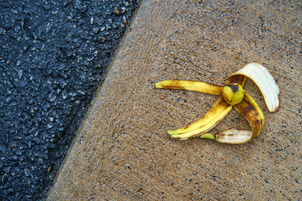 Slippery Comedy Banana Peel Slapstick slippery comedy banana peel laying on ground ready to make someone slip and fall slapstick comedy stock pictures, royalty-free photos & images