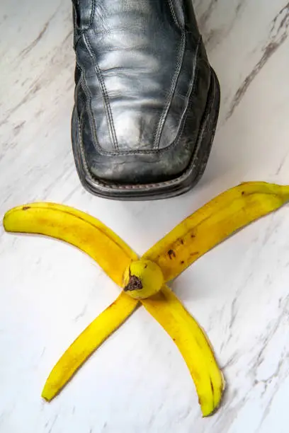 Business man stepping on comedy slippery banana peel