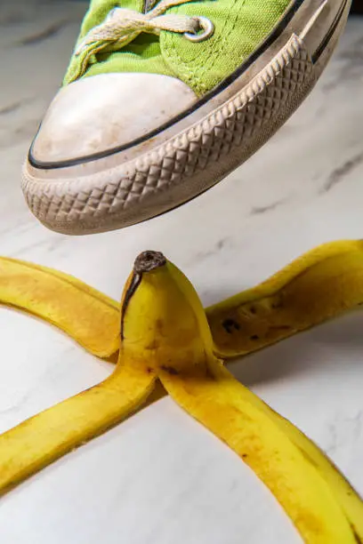 Classic slippery comedy banana peel with sneaker about to step on it