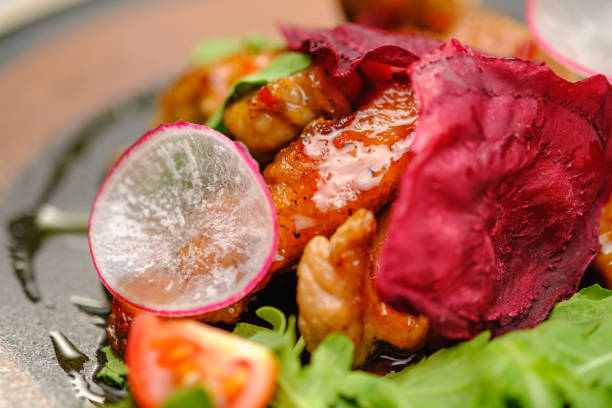 Grilled grilled meat in sauce with vegetables on a white plate.