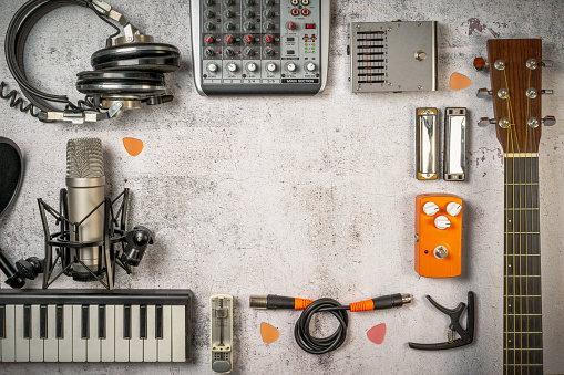 Singer-Songwriter and home recording, lifestyle music concept. Flat lay with musician and sound engineer stuff like guitar, mixer, microphone, keyboard, cables, headphones and so on. Vintage filtered