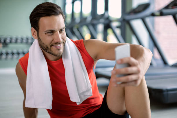 istock Happy sportsman text messaging on smart phone while relaxing in a gym. 1265282118