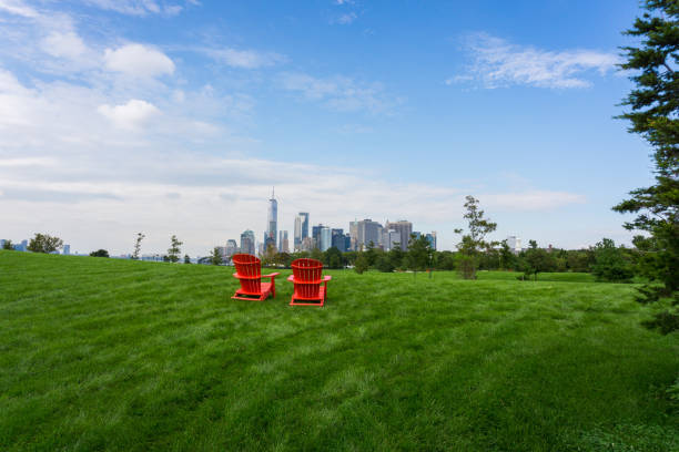 Two red chairs on a grass or a lawn, facing the skyline of Lower Manhattan In New York City Two red chairs on a grass or a lawn, facing the skyline of Lower Manhattan In New York City new york city built structure building exterior aerial view stock pictures, royalty-free photos & images