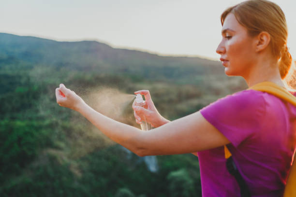 istock Woman using anti mosquito spray outdoors at hiking trip 1265283804
