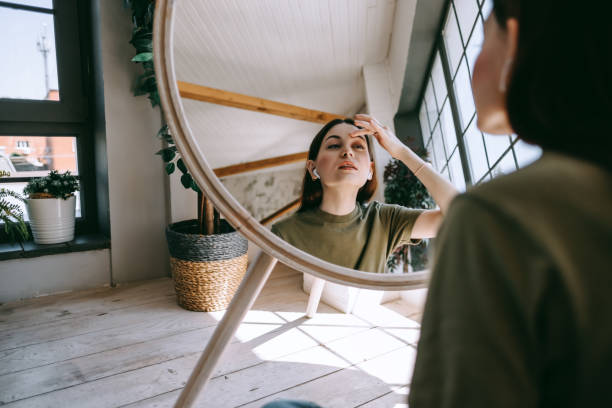 istock Attractive young caucasian woman touching face and looking at mirror 1265284554