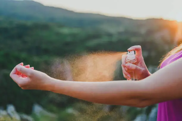 Hiker woman applying anti mosquito repellent on her hand during hiking in nature
