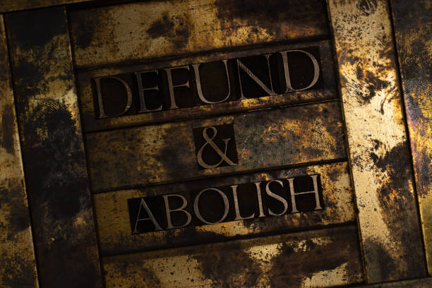 Defund and Abolish text formed with real authentic typeset letters on vintage textured silver grunge copper and gold background Typeset letters forming text over copper background marxism stock pictures, royalty-free photos & images