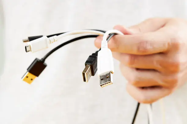 Photo of person holding stack of a different electric wires. hide computer cables