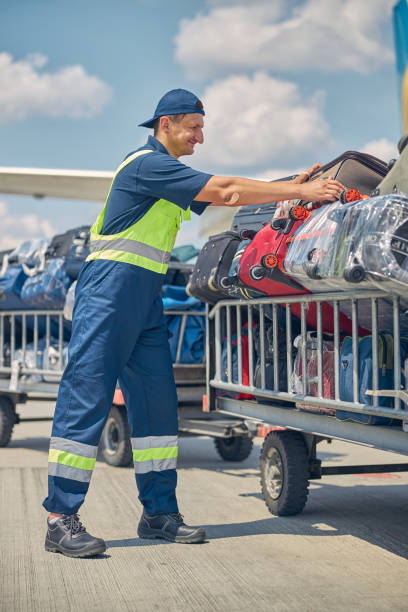 istock Man in safety overalls placing suitcases on carts 1265305340