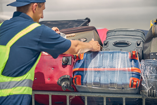 Trabajador del aeropuerto poniendo equipaje de cliente en los carritos photo