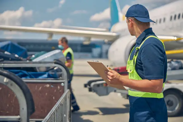 Photo of Man looking at a working baggage handler