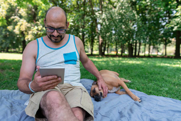 istock Man relaxing in the park with his dog 1265308610